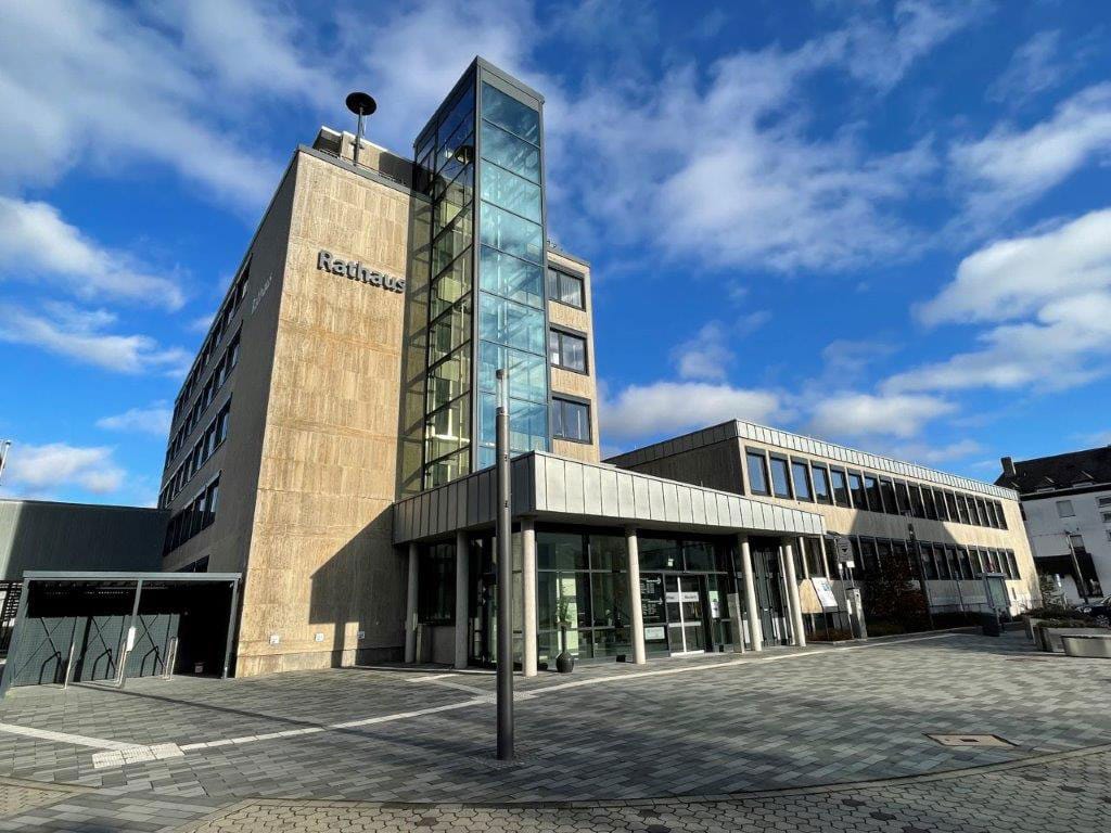 Ein modernes Gebäude mit Glasfassade und der Aufschrift "Rathaus" bei klarem Himmel.